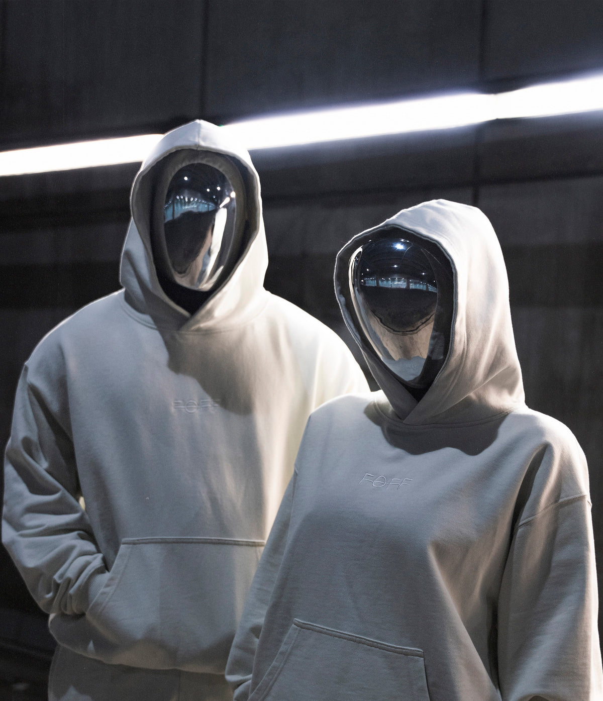 two people in FOFF masks and white oversized hoodies under strip lights, collection 02 campaign