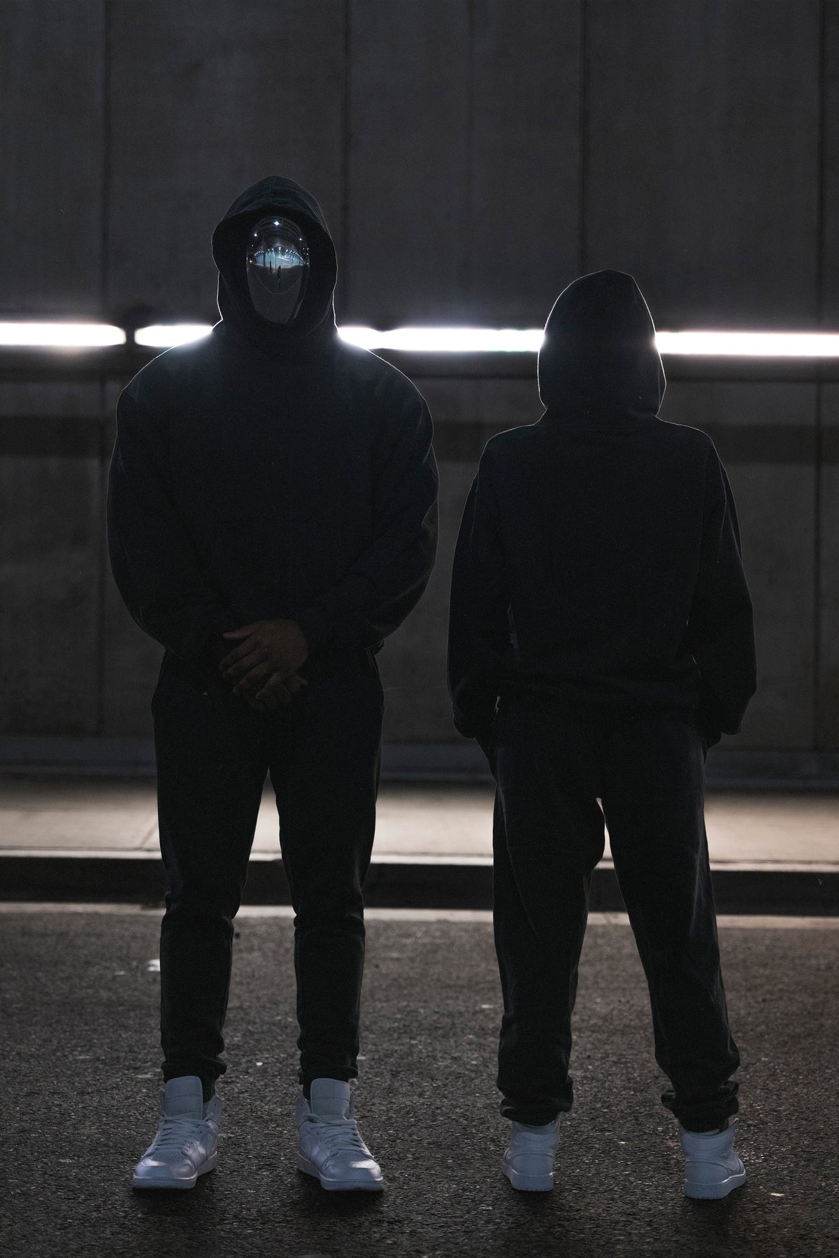 two people in FOFF masks and black hoodies standing under strip lights, collection 02 campaign